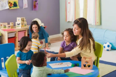 des enfants assis à la table avec une éducatrice dans une garderie