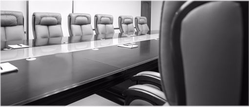 Empty boardroom with long table and chairs lining the table in black and white.