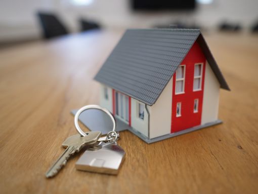 Maison miniature et clé sur un porte-clés sur une table en bois brun.