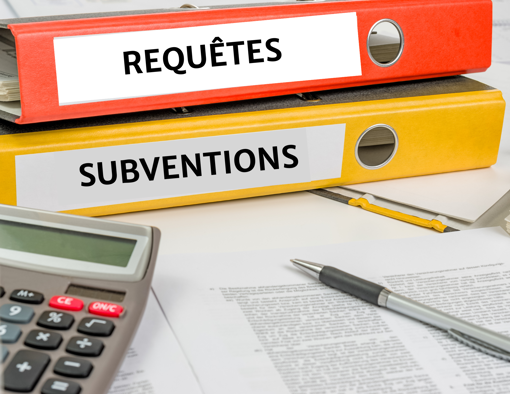 Deux cartables aves les titres requêtes and subventions écrit; calculatrice et plume sur un papier sur la table