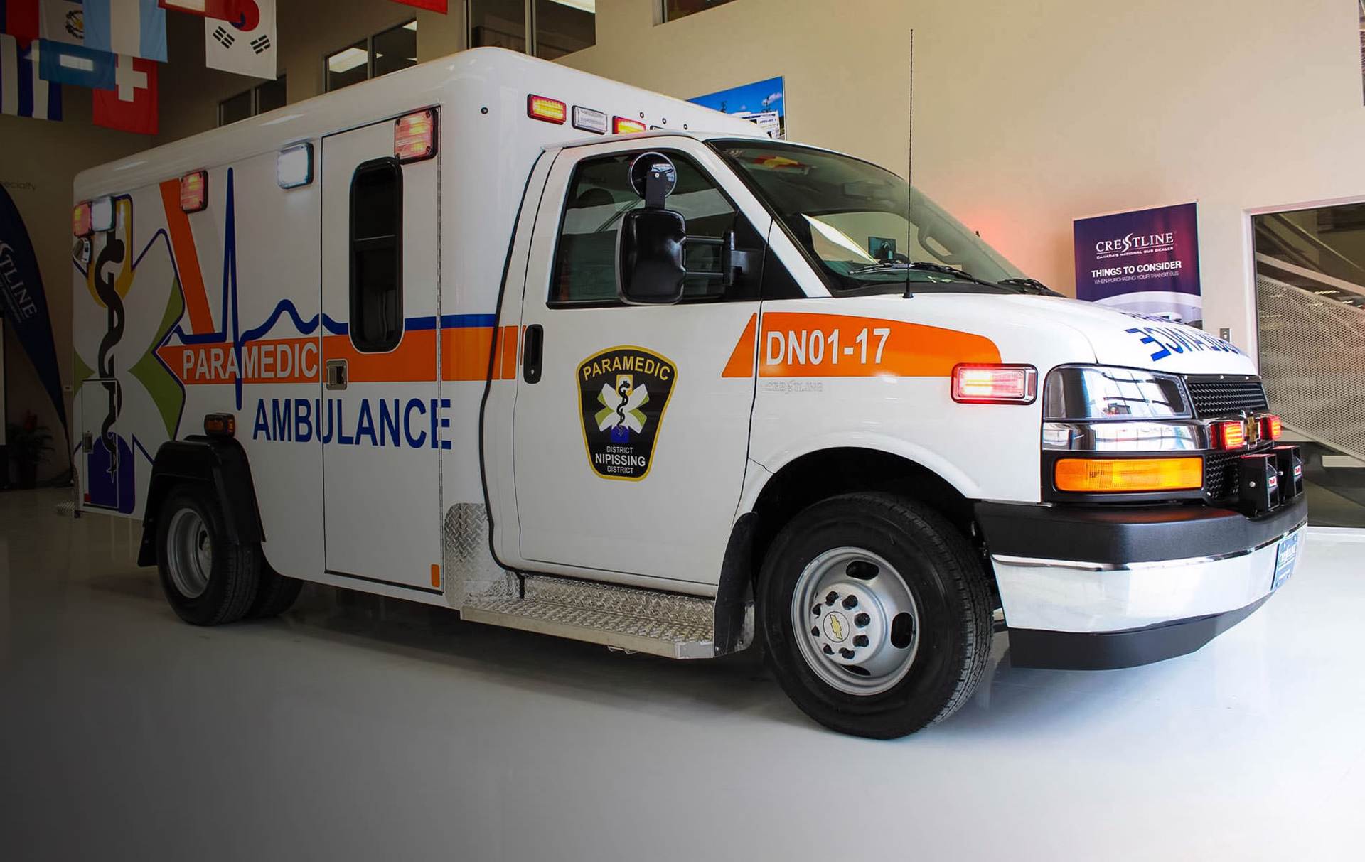 Une ambulance des services paramédicaux arborant l’image de marque du district de Nipissing est stationnée dans une baie de garage.