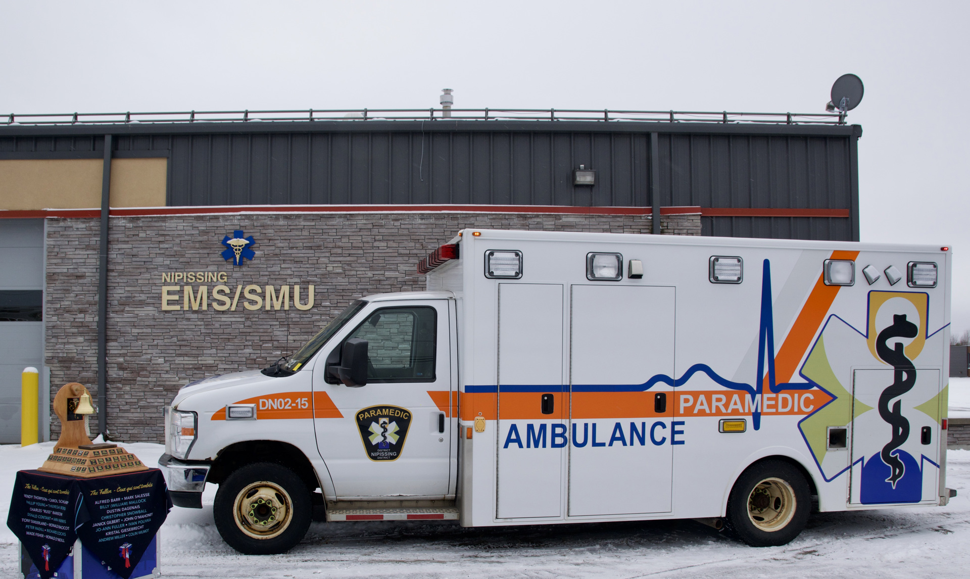 The Paramedic Memorial Bell and one District of Nipissing ambulance in front of the West Nipissing Paramedic Services base. 