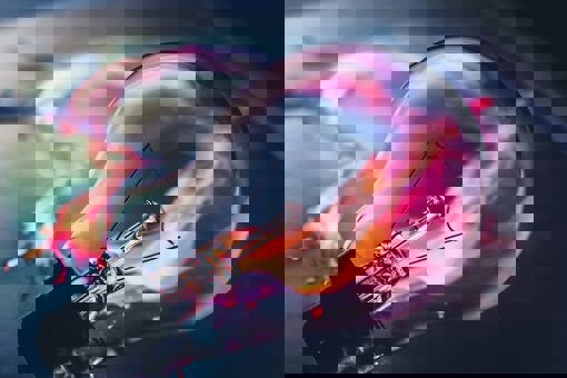 A light bulb laying on a dark table with what appears to be pink and orange fire trailing behind it.